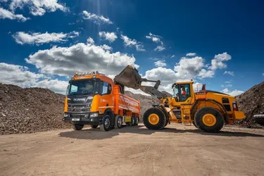tipper truck being loaded with material from large digger