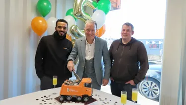 Reeko, Stuart & Ben cutting a B&A Group cake in front of balloons celebrating their 5th birthday